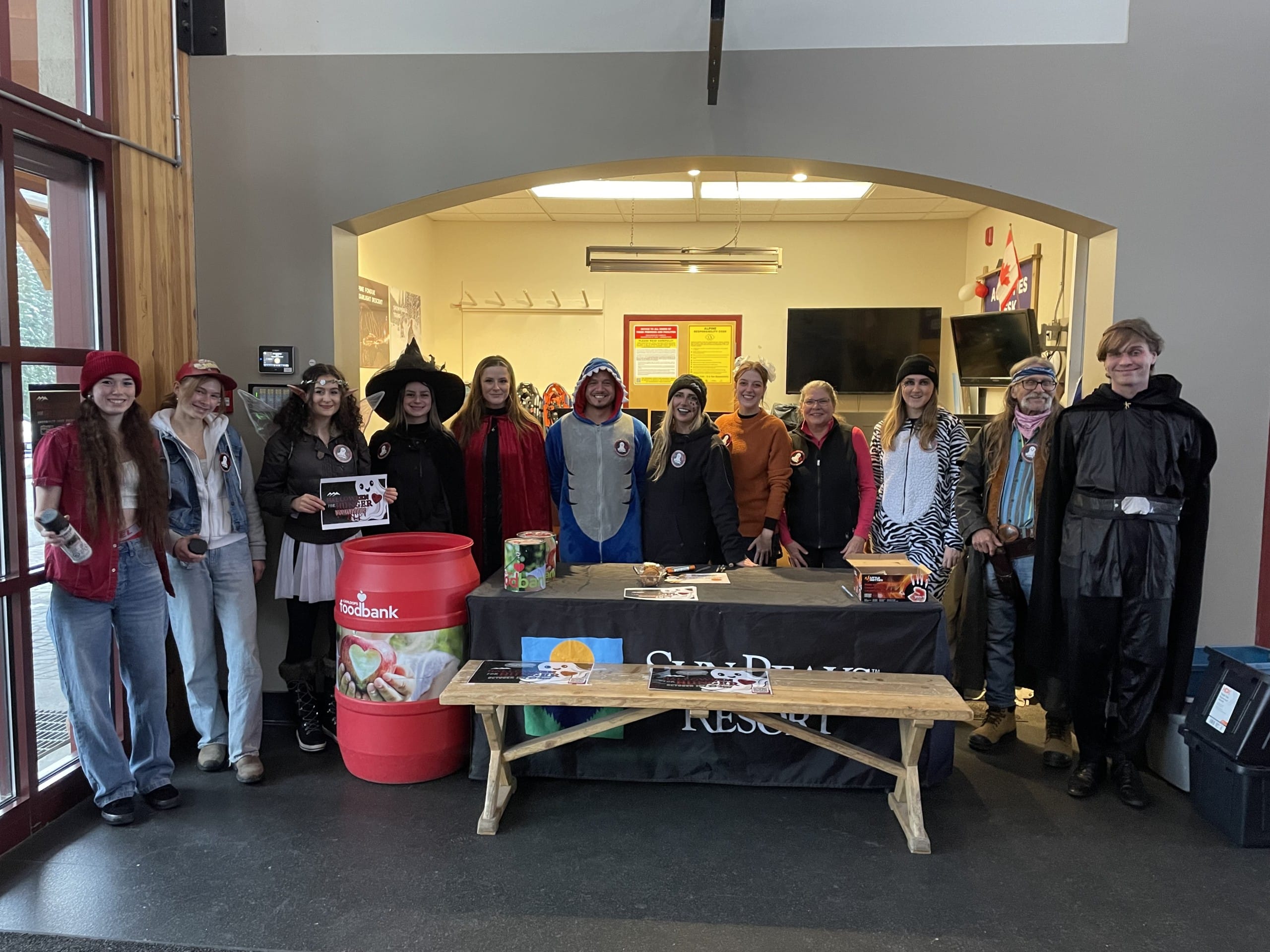 A group of volunteers stand in a line, dressed in Halloween costumes.