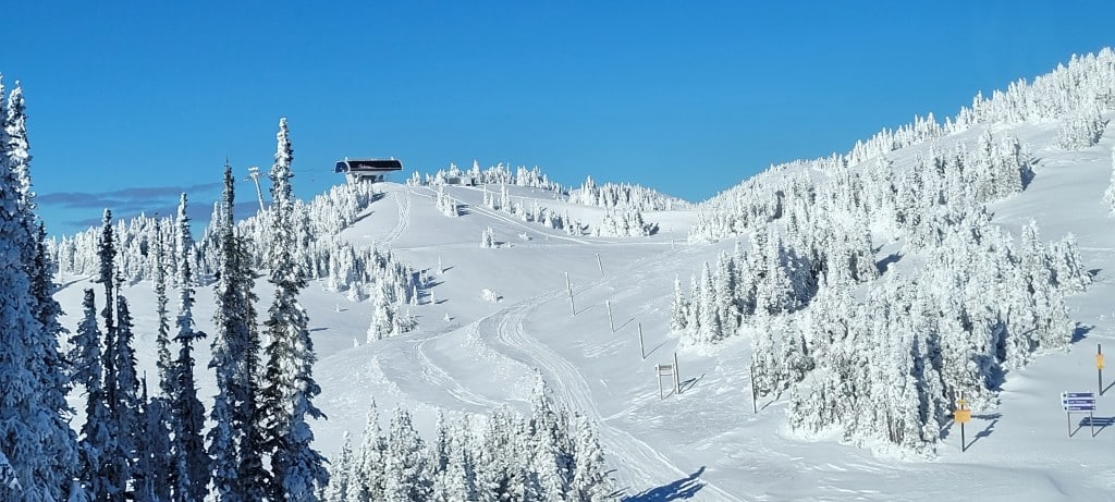 New chairlift reaching the top of the snowy West Bowl terrain in Sun Peaks.