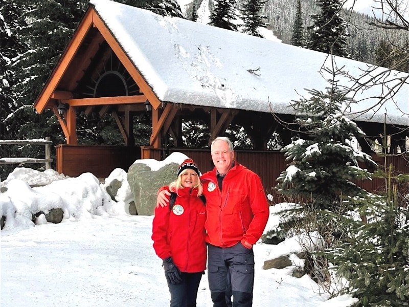 Couple poses in front of a snow-capped covered bridge.
