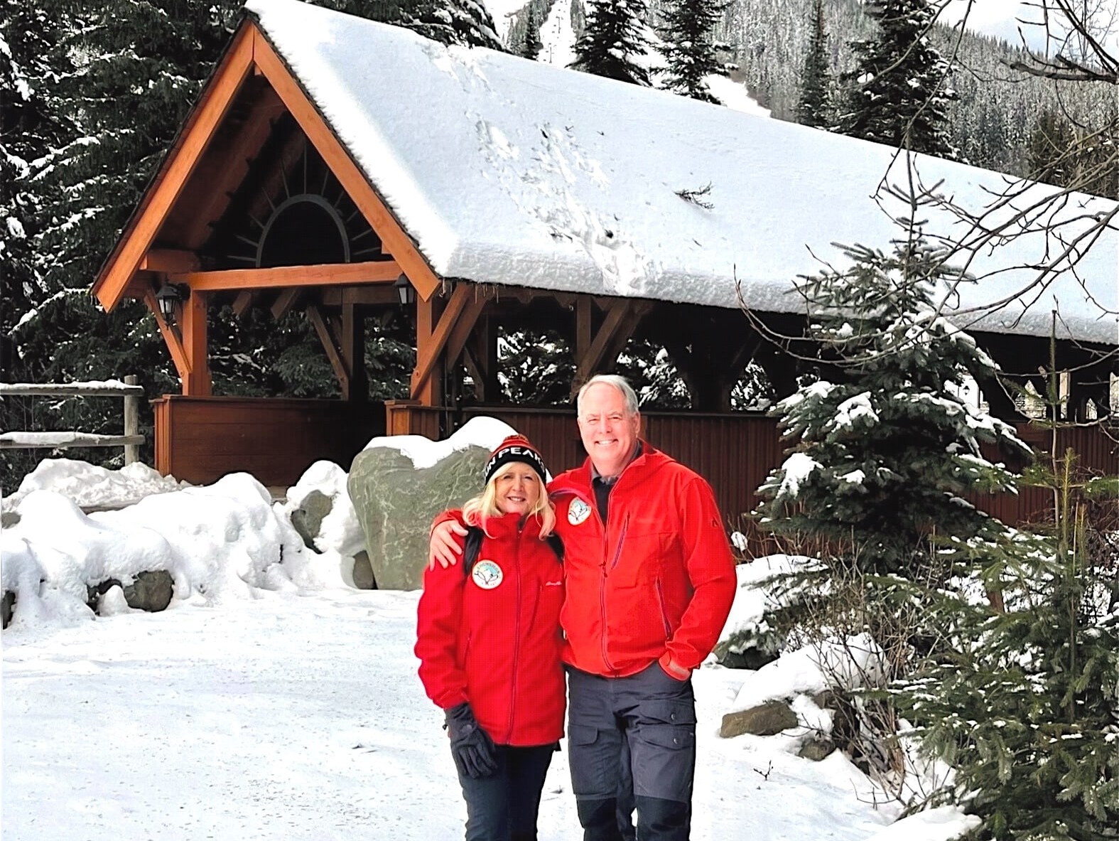 Couple poses in front of a snow-capped covered bridge.
