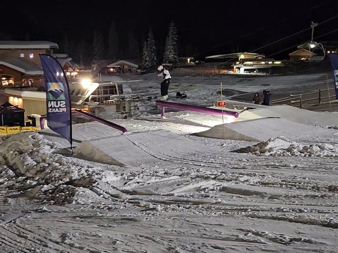 At the terrain park, the shot looks down on a skier hitting a rail.