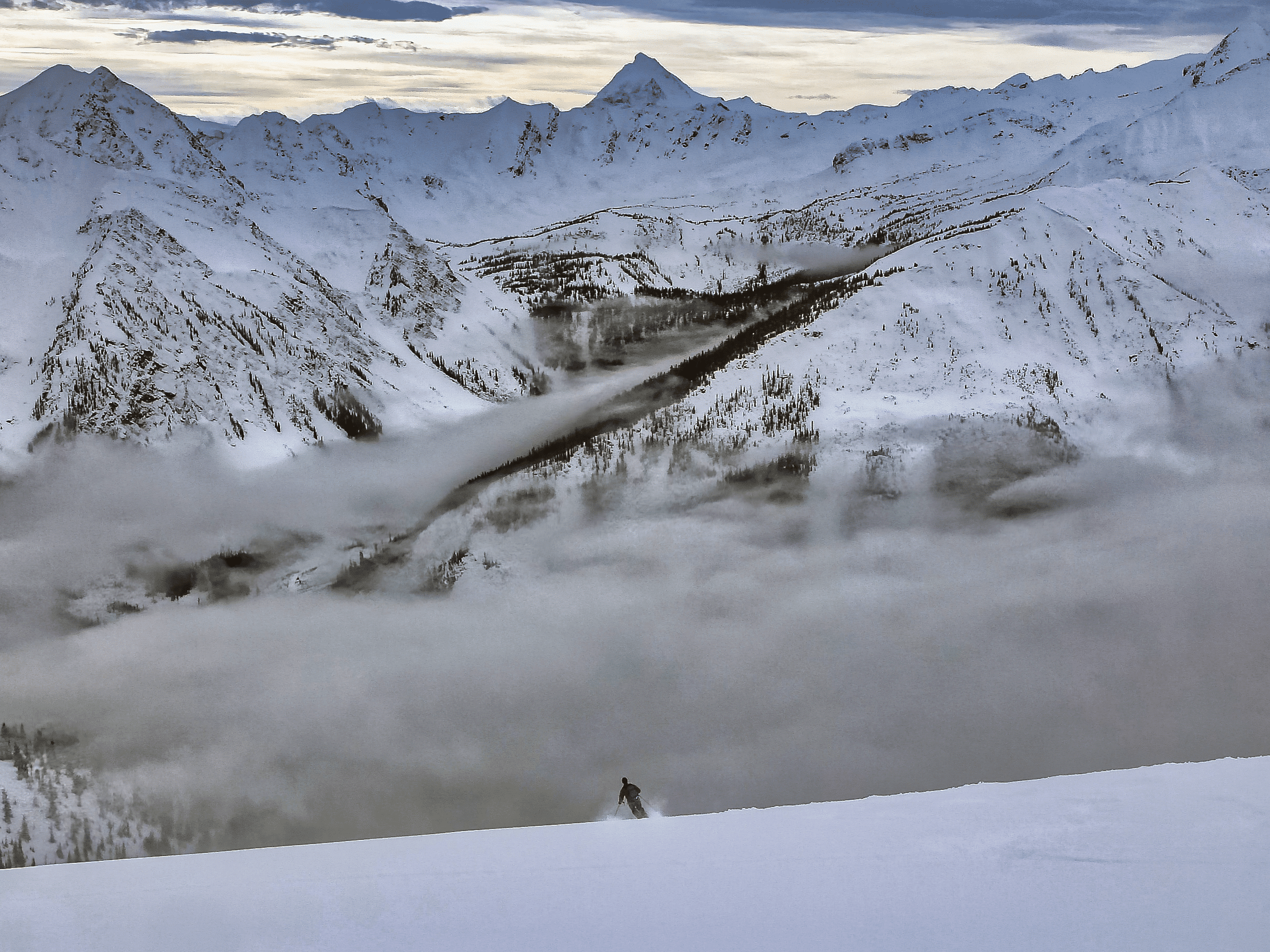 skier and snow capped mountains representing January's conditions report