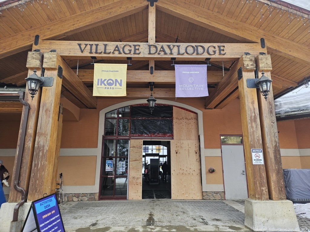 Village Day Lodge large glass doors boarded up, outside view.
